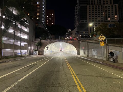 LOS ANGELES, CA, OCT 2021: Anonymous person rides a bicycle towards brightly lit Third Street Tunnel in Downtown at night