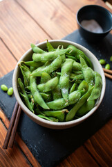 Close-up of steamed edamame sprinkled with sea salt on a dark stone board