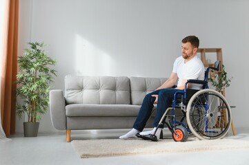 disabled man at home tries to get to his feet in a wheelchair. The concept of rehabilitation after injuries and car accidents.