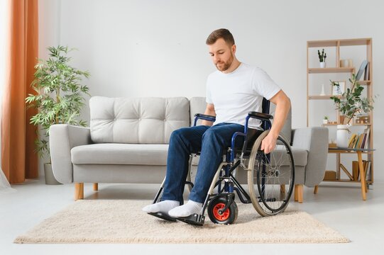 thoughtful young disabled man on wheelchair at home.