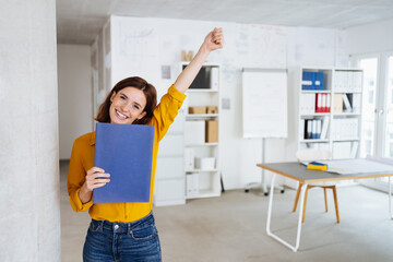 Young student stands in the office with her application documents and is happy about the new job