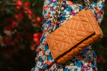 Trendy quilted faux leather orange color bag, handbag in stylish spring, summer outfit. Fashion details. Copy, empty space for text