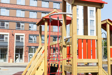 View of empty new modern children playground in courtyard of high-rise residential buildings in sunny summer day.
