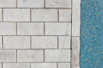 The boundary between the mulch rubber playground and the sidewalk tiles. Transition to the area for sports and playground