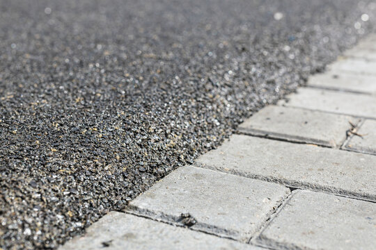 The boundary between the mulch rubber playground and the sidewalk tiles. Transition to the area for sports and playground