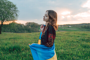 horizontal portrait of young Ukrainian woman in vyshyvanka  - ukrainian national clothes. She is holding ukrainian flag - symbol of freedom and independence. Stand with Ukraine