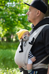 father carrying his child in a baby sling