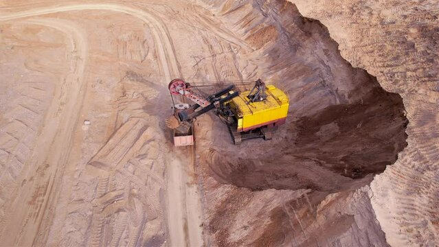 Mining excavator loads sand into dump truck. Excavator loads sand rock into a haul truck. Sand pit development. Mining industry. Electric rope shovel dropping rock ore. Sand mining in opencast. 