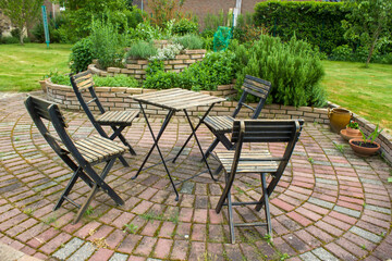 herb spiral in the garden and table with chairs