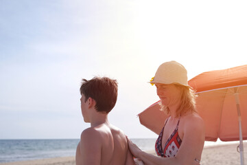 Mother applying sunscreen on son