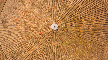 Aerial perpendicular closeup of a circular roof constructed with orange tiles.
