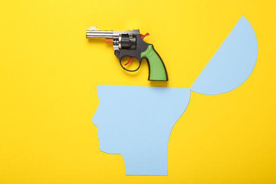 Open your mind, mental health concept, creative thinking. Paper silhouette of human head and gun on yellow background