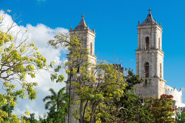 The towers of the Catholic Church are visible through the trees. Postcard, Valladolid, Mexico. Colonial architecture.