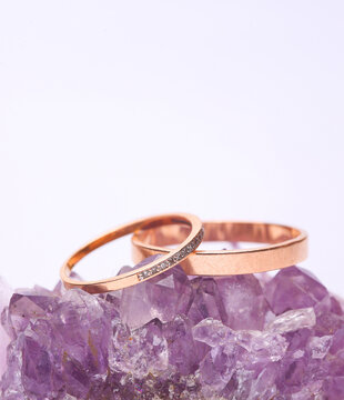 Two gold wedding rings on natural amethyst druse. Isolated on white background