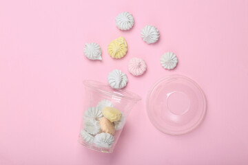 Fototapeta na wymiar Plastic cup with Sweet colored meringue on a pink background. Top view. Flat lay