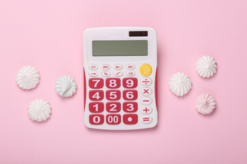 Calorie counting, diet concept. Sweet meringue with calculator on a pink background. Top view. Flat...