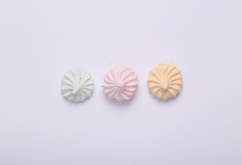 Sweet colored meringue on white background. Top view. Flat lay