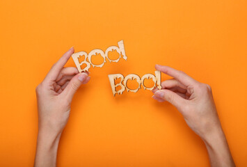 Happy halloween concept. Hands holding  word boo! on orange background. Trick or treat. Top view