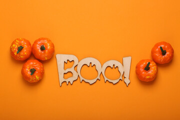 Happy halloween concept. Wooden word Boo! and pumpkins on orange background. Trick or treat. Top...