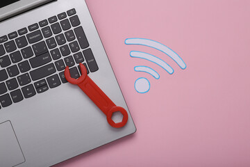 Wi-Fi connection repair concept. Wrench, laptop and waves wifi icon on pink background. Top view