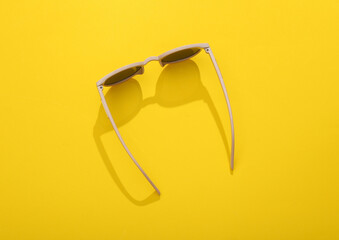 Top view stylish sunglasses on yellow bright background.