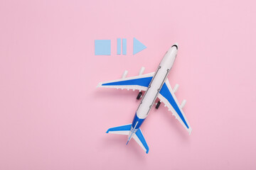 Toy air plane with icons start, stop, pause of media player on pink background. Travel concept. Top view