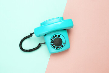 Retro blue old fashioned rotary phone on pink blue background. Top view