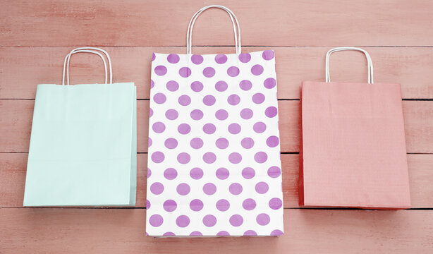 Paper shopping bags on pink wooden background. Top view