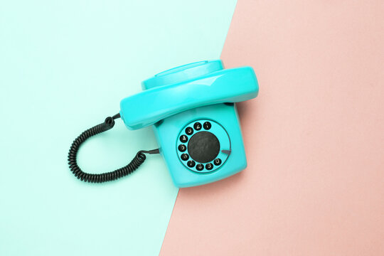 Retro blue old fashioned rotary phone on pink blue background. Top view