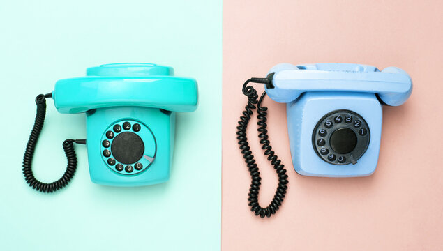 Retro blue old fashioned rotary phones on pink blue background. Top view
