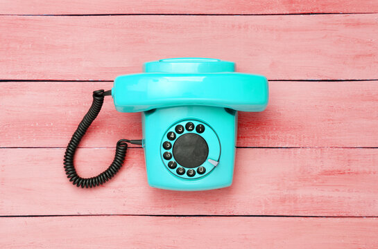 Retro old fashioned blue rotary phone on red wooden table. Top view