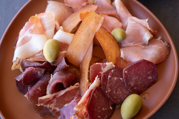 Food. Antipasti. Closeup view of meat cold cuts such as salami, ham and cured ham, and green olives...