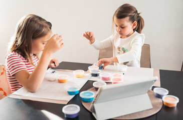 Obraz na płótnie Canvas Little girls sculpt figurines crafts from air plasticine, modeling dough.Online lessons in tablet. Children's creativity,hobby,developing activities,training,development of fine motor skills of hands