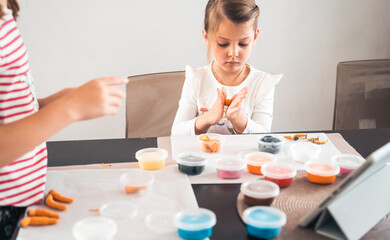 Little girls sculpt figurines crafts from air plasticine, modeling dough.Online lessons in tablet. Children's creativity,hobby,developing activities,training,development of fine motor skills of hands