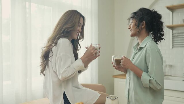 Holiday concept of 4k Resolution. Asian women having coffee together in the kitchen. Young women are in a mutual lesbian love relationship.