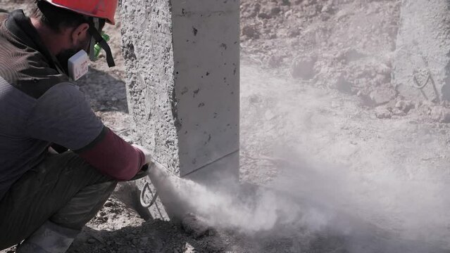 a worker at a construction site cuts concrete with a grinder