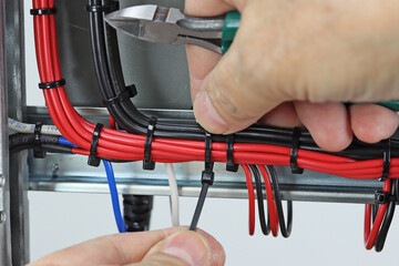 Installation of a cable tie on an insulated mounting wire in an electrical panel.