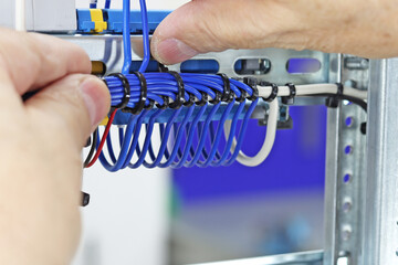 Installation of a cable tie on an insulated mounting wire in an electrical panel.