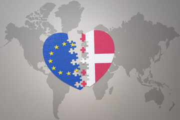 puzzle heart with the national flag of european union and denmark on a world map background. Concept.