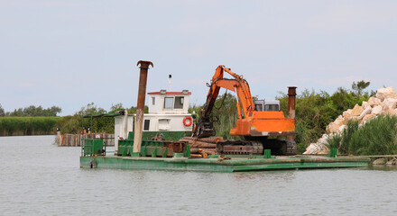 barge carrying a large digger to the construction site in the river mouth during an excavation to dredge