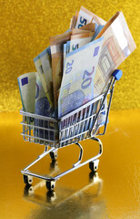 shopping trolley with lots of european banknotes the golden background symbolizing inflation and...