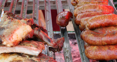 abundant mixed meat cooked on the metal grill heated by the coals and many juicy pork sausages