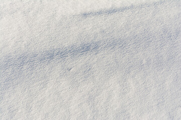 White uneven snow texture with embossed shadows. Abstract background with snowy surface in spring time.