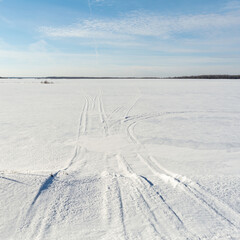 Snowmobile tracks on a winter field. Sunny winter day with blue sky