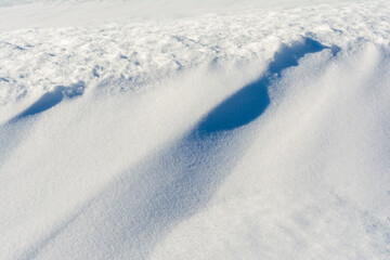White uneven snow texture with embossed shadows. Abstract background with snowy surface in spring time.