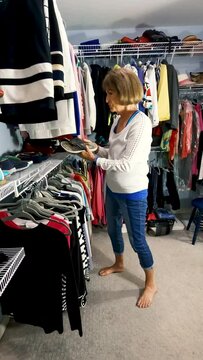 Mature woman choosing shoes in her closet