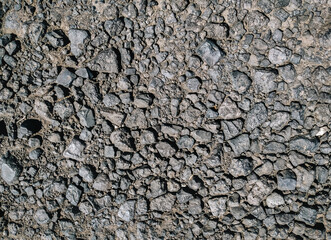 Cinder stones lie on a dirt road, top view in the rays of the midday sun.