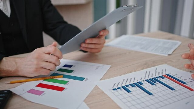 Unrecognizable businesswoman giving notepad with documents to male partner, discussing details at office