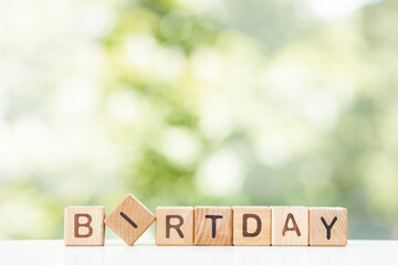 Birthday word written on wood block. Birthday text on green summer background for your design