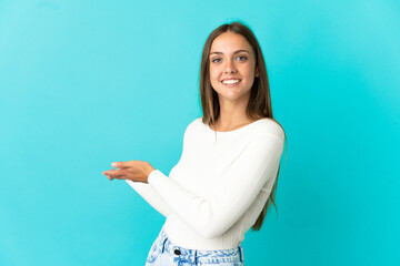 Young woman over isolated blue background extending hands to the side for inviting to come